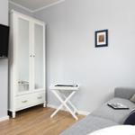 Wohnzimmer mit Sofa, Kleiderschrank und Fernseher an der Wand.