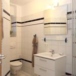 Badezimmer mit Dusche, Waschbecken und Toilette. Fliesen mit dunklen Streifen.