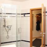 Badezimmer mit Dusche, Spiegelschrank und angrenzender Garderobe.
