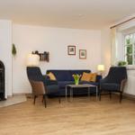 Wohnzimmer mit Sofa, zwei Sesseln, Kamin und Holzboden.