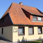 Haus mit gelbem Anstrich, rotem Dach und Fenstern mit weißen Vorhängen.