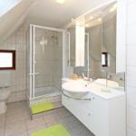 Badezimmer mit Dusche, Waschbecken und Toilette unter Dachschrägen.