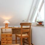 Schreibtisch mit Stuhl und Lampe unter Dachschräge. Modellboot und Vogel auf Fensterbank.