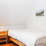 Schlafzimmer mit Holzbett, Nachttisch und Wandbildern