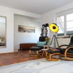 Wohnzimmer mit zwei schwarzen Sesseln, Teppich und Wandspiegel.