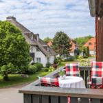 Terrasse mit Tisch und Stühlen, Blick auf traditionelle Häuser mit Schindeldächern und grüne Bäume.