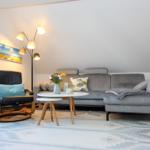 Ein Wohnzimmer mit grauem Sofa, schwarzer Sessel und runden Tischen.