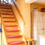 Holztreppe mit roten Matten führt zur oberen Etage. Neben einem Schrank und Küchenarbeitsplatte.