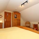 Schlafzimmer mit Holzbett, Kleiderschrank und Stuhl. Dachschrägen und Holzmöbel.