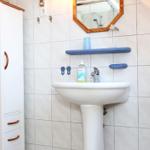 Badezimmer mit Waschbecken, Spiegel und weißen Fliesen.