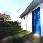 Wohnung mit blauer Tür, weißer Wand und Steinverkleidung an der Seite.