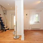 Eingangsbereich mit Holzboden, Treppe und Garderobe. Fenster mit Vorhängen und Heizkörper.