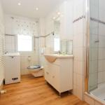 Badezimmer mit Dusche, Waschbecken, WC und Waschmaschine.