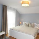 Schlafzimmer mit Bett, Nachttischen, Lampe und Wandbild.