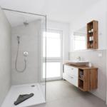 Moderne Badewanne mit Dusche, Waschbecken und Holzregal an der Wand.