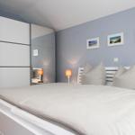 Schlafzimmer mit Bett, Kleiderschrank und Wandbildern