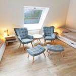 Zimmer mit zwei Betten, zwei Sesseln und einem Fenster