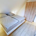 Schlafzimmer mit Doppelbett, Holzboden und Kleiderschrank.