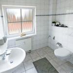 Badezimmer mit Toilette, Waschbecken und Fenster mit getöntem Glas.
