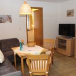 Wohnzimmer mit Sofa, Esstisch und Fernseher. Holzmöbel und Wandbild.