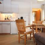 Küche mit Essbereich, Holzmöbel und Fenster. Weiße Schränke und Fliesenwand.