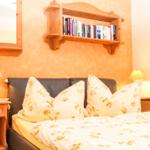 Schlafzimmer mit Bett, Nachttischen und Bücherregal an der Wand.