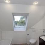 Badezimmer mit Dachfenster, Badewanne, Toilette und Waschbecken.