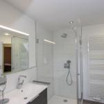 Badezimmer mit Dusche, Waschbecken und Spiegel