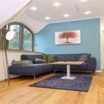 Wohnzimmer mit Sofa, Tisch und Fenster. Wandbild und Holzboden.
