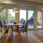 Esszimmer mit Holztisch, Stühlen und großen Fenstern zum Garten