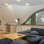 Wohnzimmer mit Sofa, Couchtisch und TV unter schrägen Dachfenstern.