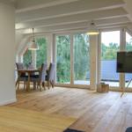 Wohnbereich mit Essbereich, Holzboden und großem Fenster. Fernseher auf Stativ.