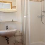 Badezimmer mit Dusche, Waschbecken und Spiegel.