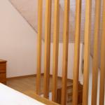 Schlafzimmer mit Holzbalken, Nachttisch und Lampe unter schrägem Dach