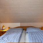 Doppelbett mit Streifenbezug, zwei Nachttische und Holzdecke.
