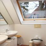 Badezimmer mit zwei Waschbecken, Dachfenster und Toilette.