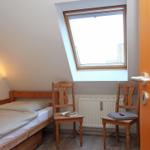 Ein Schlafzimmer mit Dachschrägen, einem Bett, zwei Stühlen und einem Dachfenster.