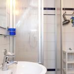 Bad mit Dusche, Waschbecken und blauen Behältern.