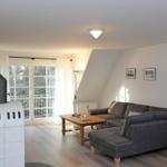 Wohnzimmer mit Sofa, Holztisch und Schiebetür zum Balkon.
