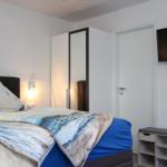 Schlafzimmer mit Bett, Wandbild, Spiegelschrank und Flachbildfernseher.