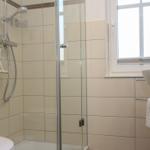 Badezimmer mit Dusche, Waschbecken und Fenster.