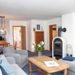 Wohnzimmer mit Sofa, Couchtisch und Kaminofen. Küche und Schlafzimmer sind sichtbar.