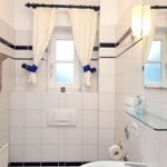 Badezimmer mit Fenster, Spiegel und Toilettenpapierhalter