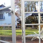 Durch die Glastüren ist ein Garten mit Liegestuhl und Sonnenschirm zu sehen.