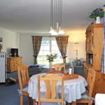 Esszimmer mit Holztisch und Stühlen. Wohnbereich mit Sofa und Kaminofen.