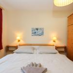 Schlafzimmer mit Doppelbett, Holzschrank und Wandbild mit Vogel.