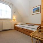 Ein Schlafzimmer mit Holzbett, Fenster und Wandleuchte.
