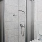 Dusche mit Handbrause und Waschmaschine in Badezimmer