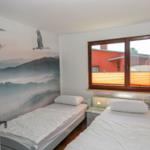 Zwei Einzelbetten mit weißen Bettwäsche. Wandbild mit Schwanen und Bergen. Fenster mit Holzrahmen.