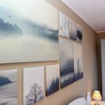 Wand mit mehreren Landschaftsbildern in Blau- und Grautönen, daneben Schrank und Nachttischlampe.